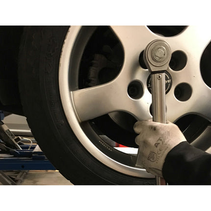 the mechanic is using a torque wrench to tighten up the new wheel nuts on the car